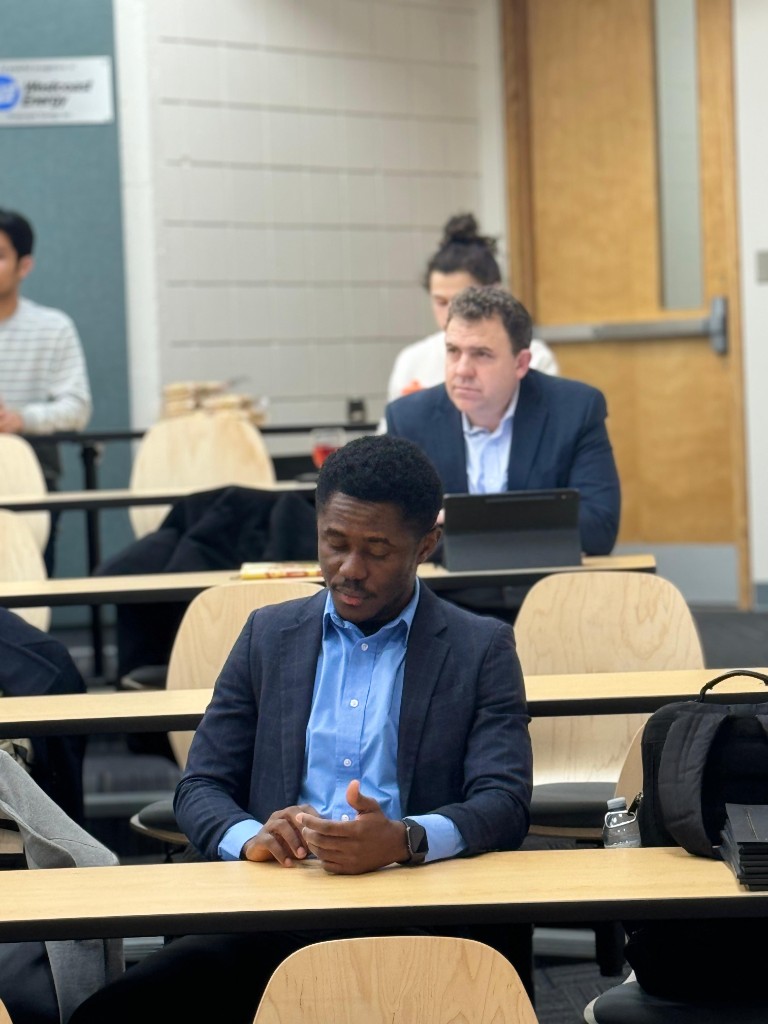 George Amoako seated during a UNBC Investment Club meeting